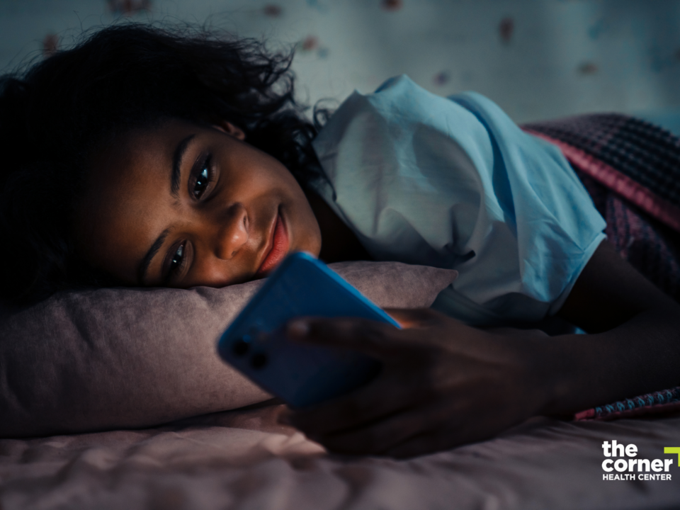 Teen girl laying in bed in the dark and staring at her phone.